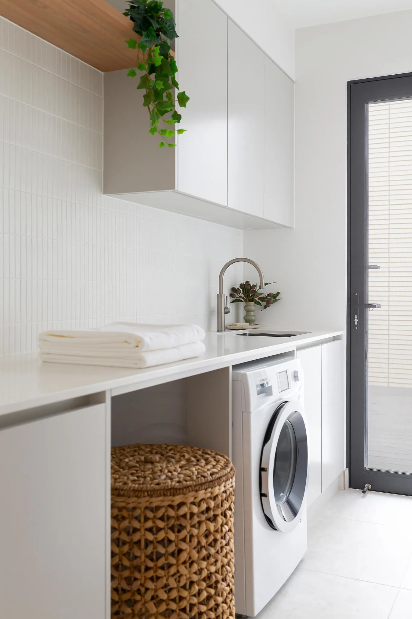 Renovated laundry with white cabinetry and modern tapware